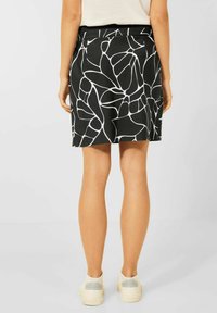 Černá sukně s bílým abstraktním vzorem listů, s úzkým pasem a rozšířeným střihem. Nosit s bílými teniskami.