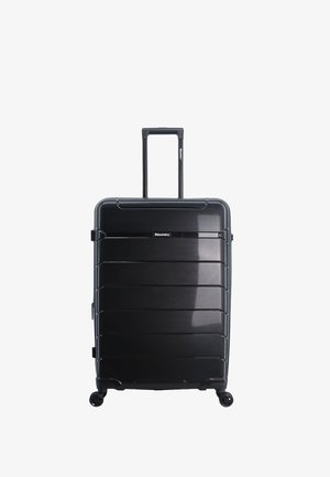 Maleta rígida negra con estrías horizontales, asa retráctil y cuatro ruedas para facilitar su movilidad; presenta un logo en la parte frontal.