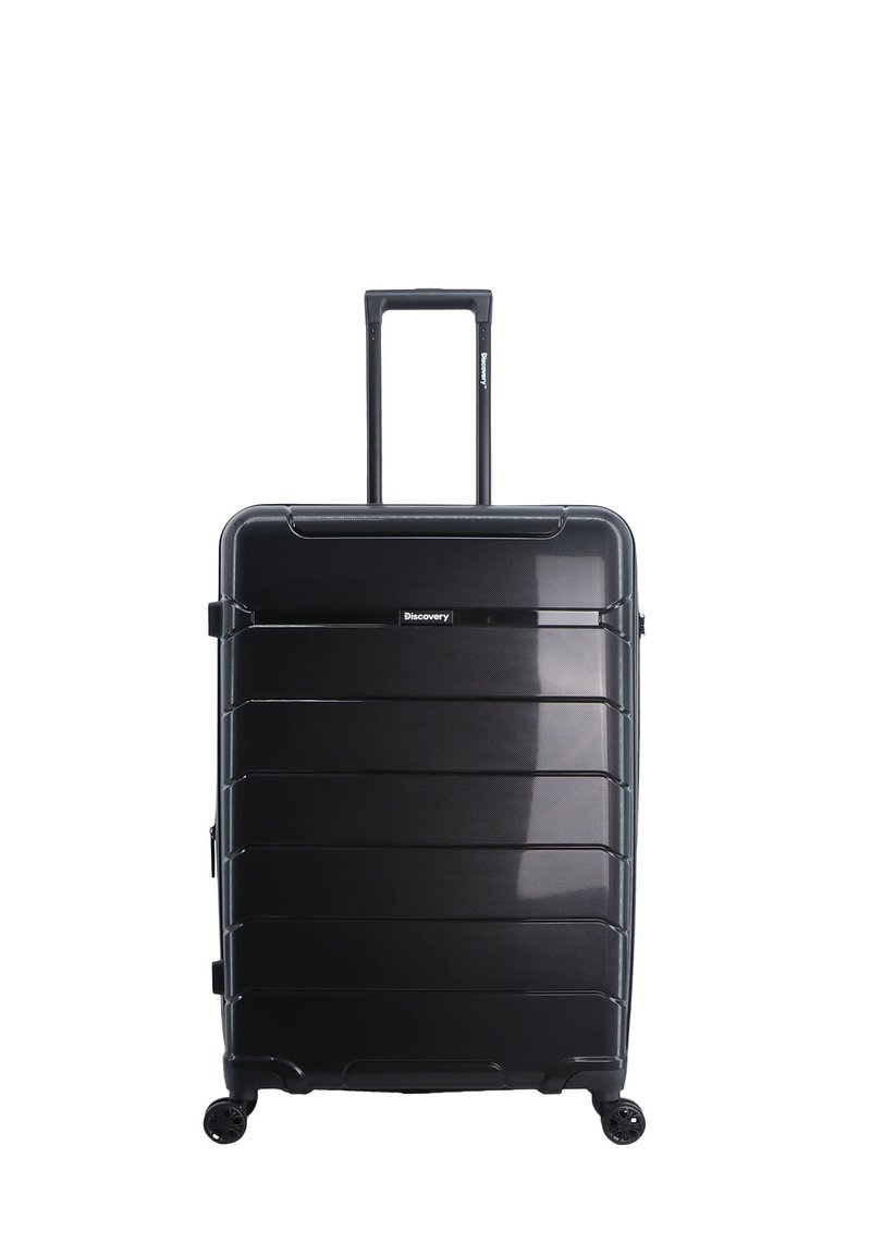 Maleta rígida negra con estrías horizontales, asa retráctil y cuatro ruedas para facilitar su movilidad; presenta un logo en la parte frontal.