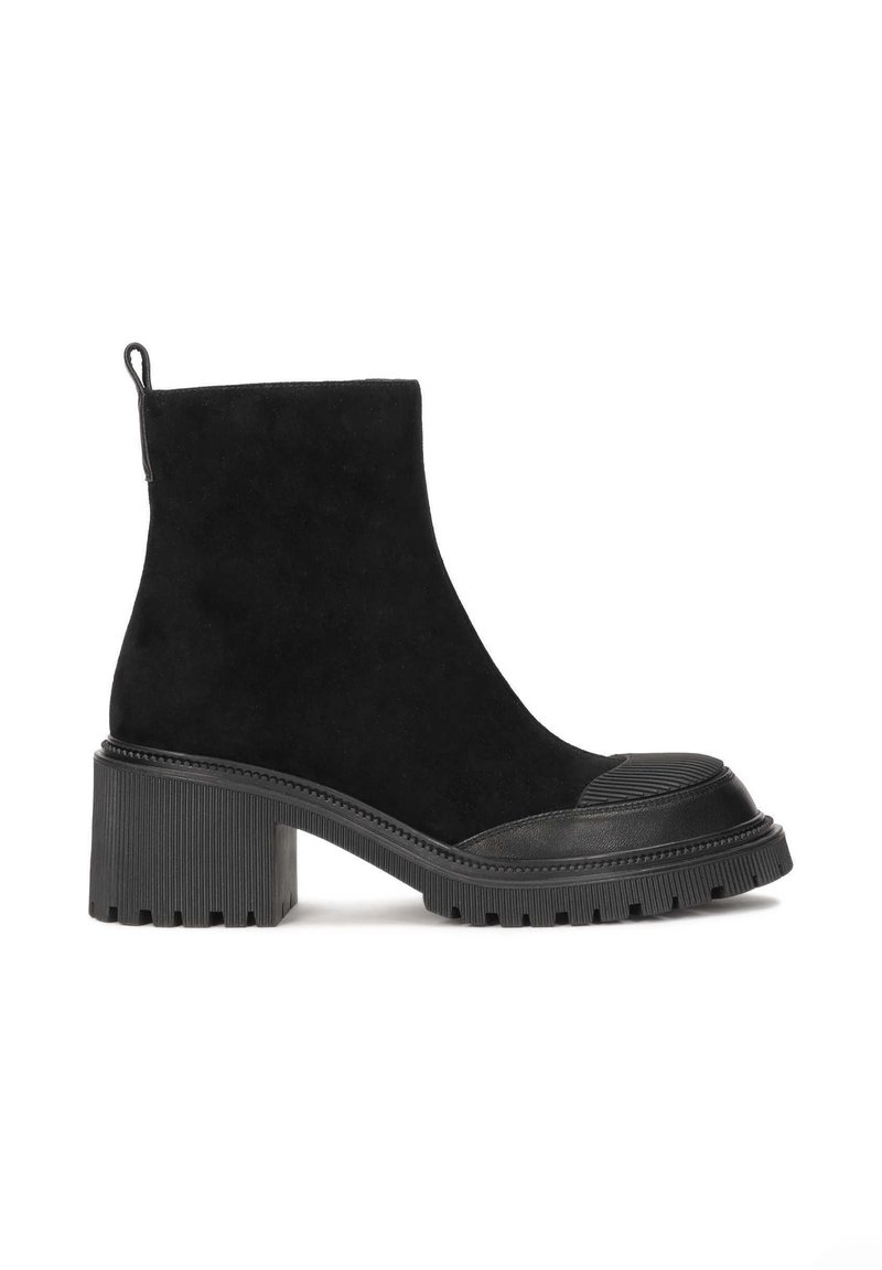 Botines negros de ante y goma con un tacón grueso y estriado y una parte delantera lisa. Cuenta con una tira para facilitar su puesta.