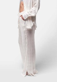 Leichtes, weiß gestreiftes Loungewear-Set, bestehend aus einem knöpfbaren Hemd und Hose mit Kordelzug, seitlichen Schlitzen und gerafftem Saum. Weicher, strukturierter Stoff.