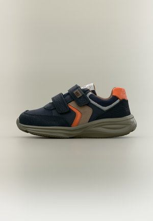 Παιδικό sneaker σε ναυτικό μπλε με μπεζ και πορτοκαλί λεπτομέρειες, δύο αφαιρούμενους ιμάντες με βέλκρο και γκρι σόλα σε απλό φωτεινό φόντο.