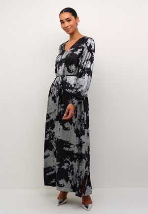 Maxi jurk in zwart en grijs tie-dye patroon, lange mouwen, V-hals, strakke taille met riem, zijsplitsen, zachte stof, gepolijste zilveren hakken.