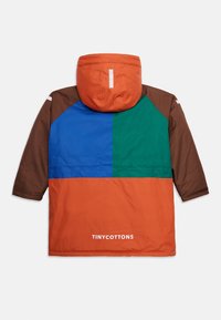 Veste d'hiver avec capuche pour enfants, aux blocs de couleurs orange, bleu, vert et marron, dotée d'une bande réfléchissante et du texte "TINY COTTONS".