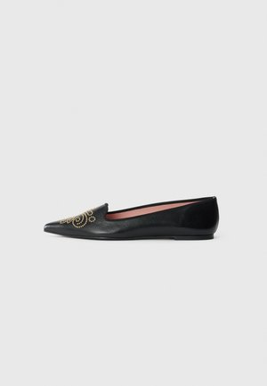 Black leather flat shoe with pointed toe and gold stud swirl decoration on front, low heel, and pink interior lining.