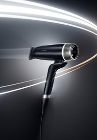 Sèche-cheveux ghd speed noir et élégant avec affichage LED de la température, poignée inclinée et effets de flux d'air sur un fond dégradé sombre.