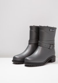 Grijze rubberen enkellaarsjes met een gestructureerde afwerking, voorzien van een brede band en een gespdetail. Verhoogde hak en geribbelde zool voor grip.