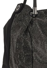 Sac à main noir avec un design texturé orné de clous argentés et une section en tissu lisse, surmonté de deux poignées noires robustes.