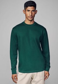Langärmliges Shirt in Dunkelgrün, Rundhals-Design, aus weichem Material, mit gerippten Bündchen und geradem Saum.