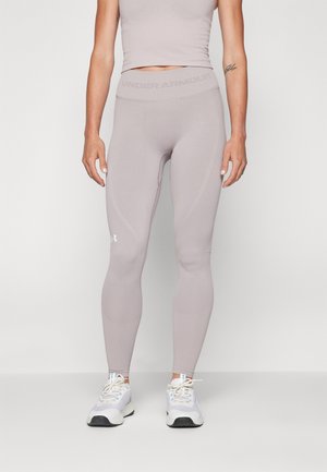 Leggings ajustés de couleur mauve clair en tissu extensible, présentant une texture lisse et le logo Under Armour au niveau de la taille et du mollet.