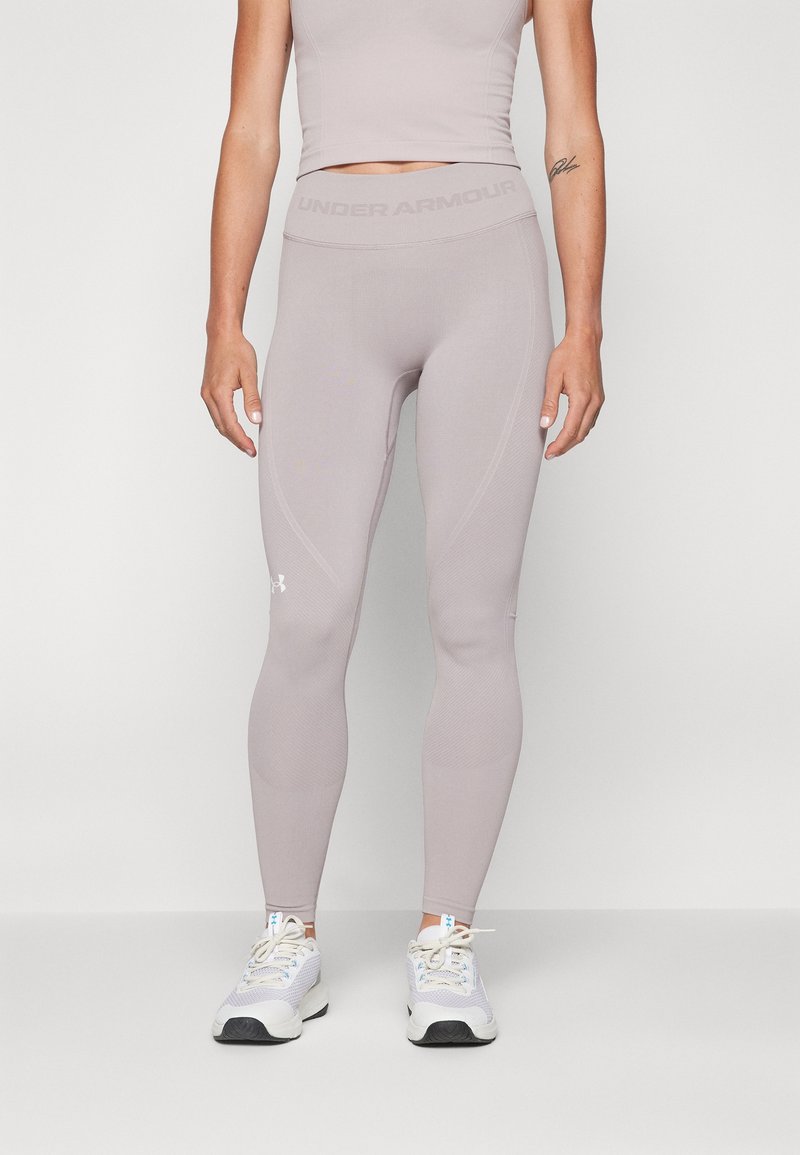 Jasnolavendowe legginsy dopasowane wykonane z elastycznego materiału, z gładką fakturą i logo Under Armour na pasie i łydce.