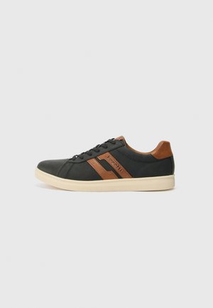 Black sneaker with brown leather accents and logo; features a smooth upper, round toe, and lace-up closure. Cream rubber sole.