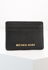 Czarny skórzany etui na karty o teksturowanej powierzchni, z czterema przegródkami na karty oraz złotym logo "MICHAEL KORS" wyraźnie umieszczonym z przodu.