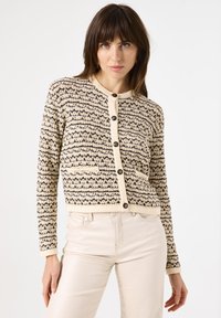 Strickcardigan in Beige mit einem schwarzen geometrischen Muster; verfügt über einen runden Halsausschnitt, Knöpfe auf der Vorderseite und zwei Vordertaschen.