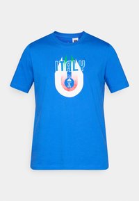 Zils īsroku T-krekls ar uzrakstu "ITALY" un stilizētu Itālijas karoga dizainu virs apaļa futbola emblēmas priekšpusē.
