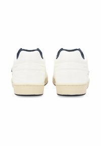 Zapatillas blancas con un upper de cuero suave, acentos de ante azul marino en el talón y una suela de goma beige. Presenta detalles de costura.
