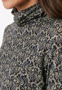 Rollkragenpullover mit einem strukturierten Muster in wirbelndem Marineblau und Creme, aus weichem, gestricktem Stoff und mit engem Sitz am Kragen.