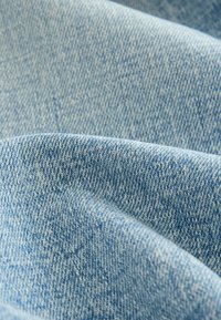 Lichtblauw denimstof met een twillbinding, voorzien van een zachte textuur en subtiele kleurvariaties, met fijne stikdetails.