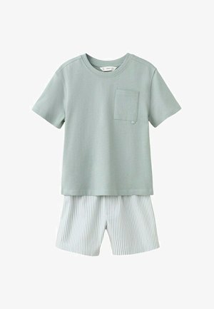 Maglietta verde salvia a maniche corte con taschino sul petto abbinata a pantaloncini bianchi con sottili righe verticali grigie.