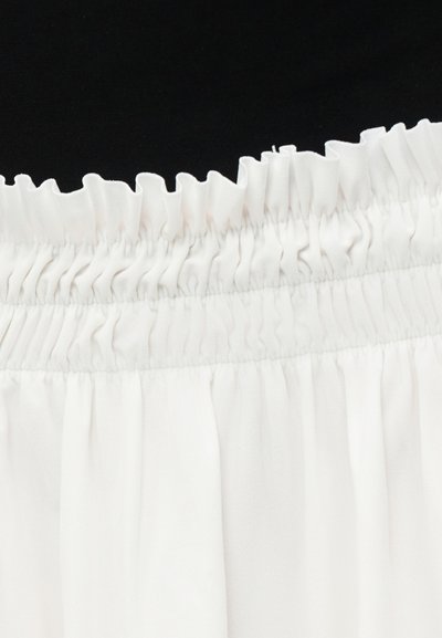 Λευκό ύφασμα με συλλεγμένη, σούρα ελαστική μέση και διακριτικές ραφές σε μαύρο φόντο.