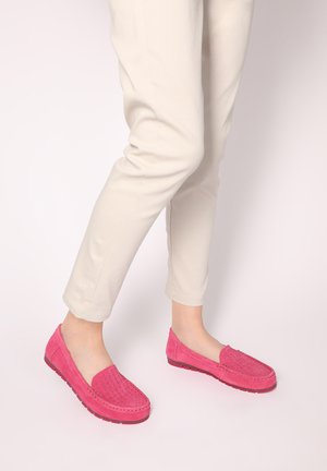 Pink suede slip-on shoes with a textured front, low profile, and rubber soles, paired with light-colored cropped pants.