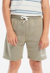Khaki-Shorts mit elastischem Bund, weißem Kordelzug und Logo-Detail. Weicher Stoff, lockere Passform und gesäumte Kanten.