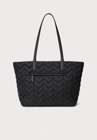 Crna prešivena velika torba s uzorkom cik-cak, s dvije crne trake, zatvaranjem na vrhu na patentni zatvarač i prednjim džepom na patentni zatvarač za dodatni prostor.