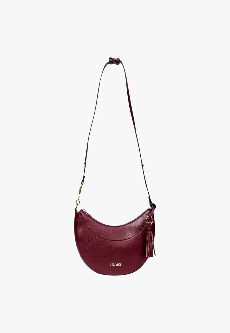 Bordeaux læder crossbody taske med en buet form, frynse detaljer og justerbar sort rem. Har et guld logo på fronten.