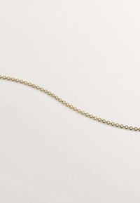 Cadena metálica de color dorado con eslabones circulares, que presenta una textura lisa y una forma curva continua, exhibida sobre un fondo claro.