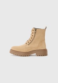 Bottines en suède beige avec une fermeture éclair latérale, des lacets à l'avant, une semelle en caoutchouc robuste et des détails texturés.