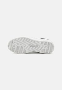 Fehér sneaker talp textúrált gumi mintázattal, hatágú taposókkal és sima felülettel. A szимен "Reebok" logó található az oldalon.