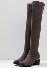 Botas de ante gris por encima de la rodilla, con punta redondeada, tacón ancho y textura suave, que presentan un diseño elegante y minimalista.