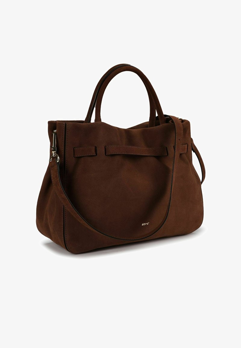 Sac cabas en daim marron avec deux poignées courtes et une bandoulière détachable. Il présente un design simple et un logo de marque subtil sur le côté.