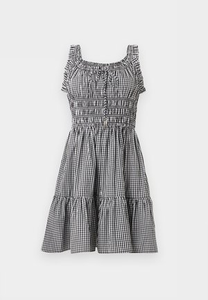 Robe sans manches en vichy noir et blanc avec bretelles à volants, corsage smocké, détail noué au niveau de l'encolure et jupe à étages.