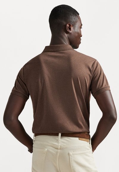 Polo shirt castanho de mangas curtas, feito de algodão, com colarinho clássico e textura subtil, combinado com calças e cinto na cor creme.