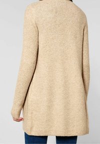 Beżowy sweter z dzianiny, z długimi rękawami, luźnym krojem i ściągaczami przy nadgarstkach. Teksturowana tkanina o miękkim wyglądzie i lekko wydłużonym tyle.