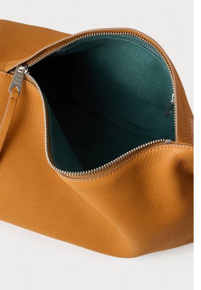 Sac en cuir fauve ouvert avec surface texturée et fermeture éclair argentée visible, montrant la doublure intérieure en tissu vert foncé.