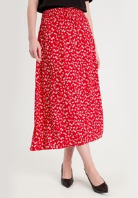 Jupe midi rouge à fleurs, comportant une taille froncée, de petits motifs floraux blancs, un design fluide et un tissu léger.