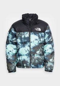 Gewatteerd jack gemaakt van synthetische stof, met een zwart bovenstuk en een blauwgroen tie-dye patroon, voorzien van een hoge kraag en een rits aan de voorkant.