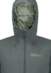 Giacca impermeabile verde scuro con cappuccio, dotata di un esterno liscio, chiusure a toggles regolabili e un logo sul petto.