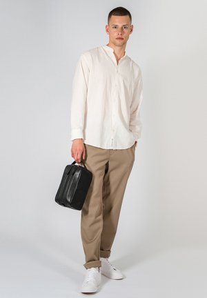 Chemise en lin beige clair, pantalons marron, baskets blanches et un sac en cuir noir. La chemise a un col boutonné et une coupe décontractée.