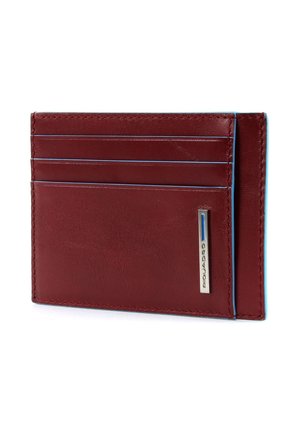 Portafoglio in pelle rossa con quattro slot per carte, cuciture blu a contrasto e un logo argentato sul lato. Design sottile e rettangolare.