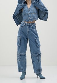 Denimoutfit med en kortad väst med knappar och fickor, i kombination med lösa cargobyxor med flera sidofickor, i ljusblå tvätt.