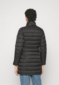 Abrigo acolchado negro con diseño de costuras, cuello alto y mangas largas. Textura suave, longitud a la cadera y silueta ajustada.