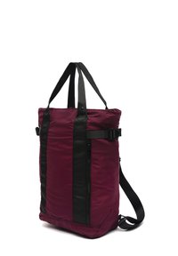 Bordo torba na rame s crnim trakama i detaljima, s patentnim zatvaračem i podesivom naramenicom, izrađena od glatkog, izdržljivog materijala.