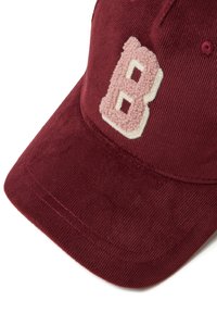 Cappello bordeaux in cotone a coste con un logo "B" ricamato di un tenue rosa chiaro sulla parte anteriore, dotato di visiera curva e cuciture sottili.