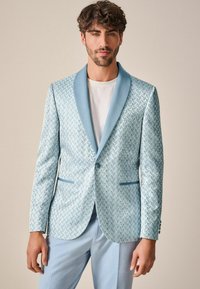 Blazer azzurro chiaro con motivo, texture liscia, colletto in raso a revers e tasche frontali, abbinato a una t-shirt bianca e pantaloni azzurro chiaro.