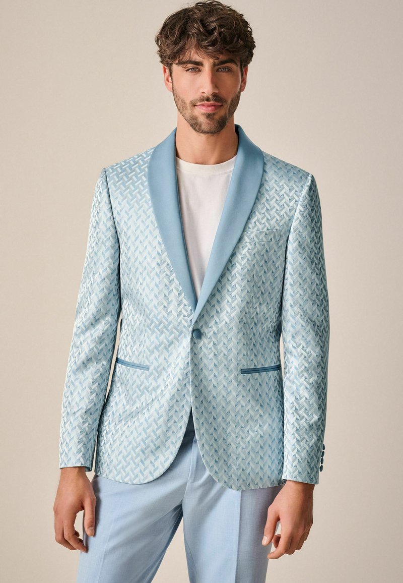 Blazer azzurro chiaro con motivo, texture liscia, colletto in raso a revers e tasche frontali, abbinato a una t-shirt bianca e pantaloni azzurro chiaro.