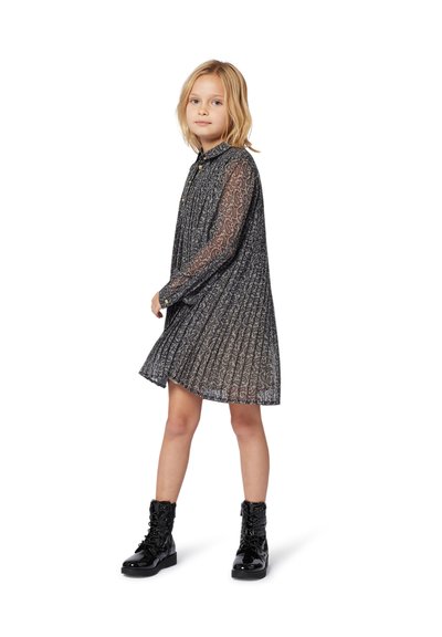 Robe à motifs noirs et gris avec des manches longues en tulle, un col à boutons et un design plissé. Associée à des bottes noires brillantes à lacets.