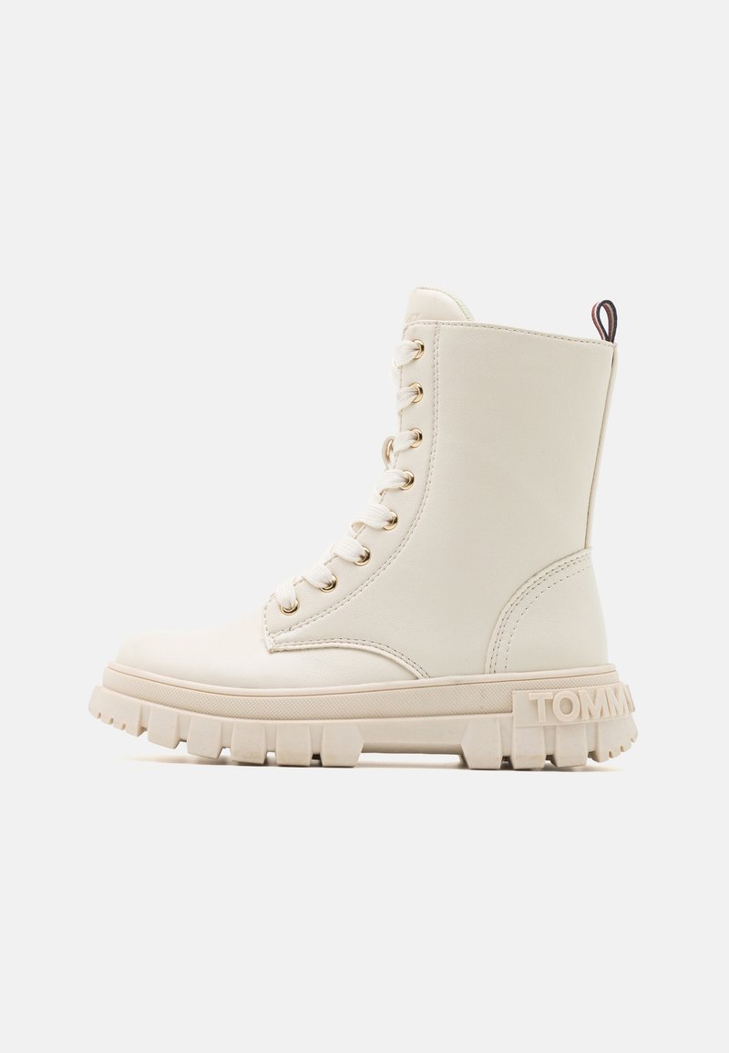 Crème leren enkelboot met een chunky zool, voorzien van beige veters en gouden hardware. Logo in de hak geperst, contrasterend label aan de achterkant.